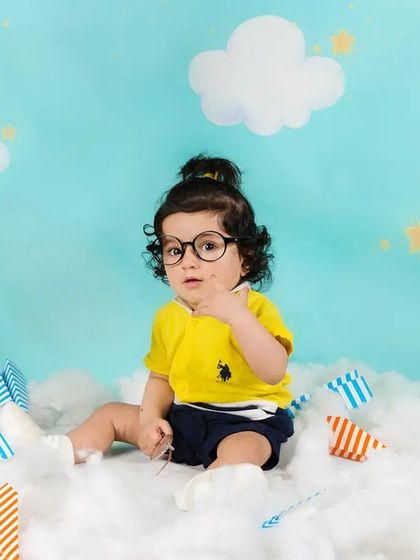 This little aviator looks very studious with his glasses on, surrounded by paper airplanes and clouds.