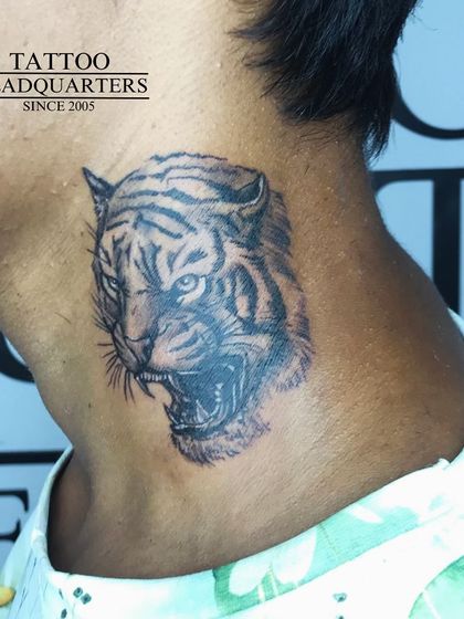 A fierce tiger head tattooed on the neck. The detailed line work and shading capture the animal's raw power and intensity.