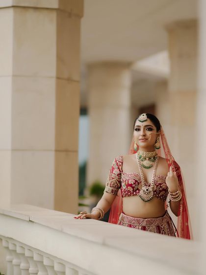This bride looks absolutely regal against the architectural backdrop. The makeup was designed to enhance her features and complement her magnificent red and green bridal ensemble.