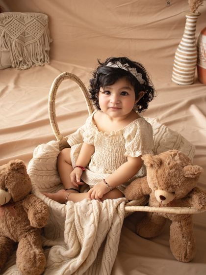 A sweet sitter session with a boho theme. This little one is nestled in a basket with her teddy bears, looking absolutely adorable.