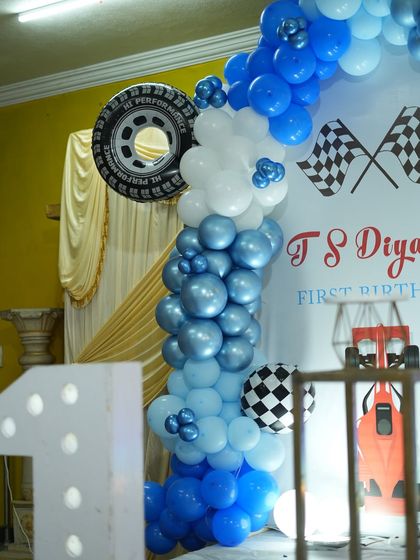 We incorporated fun elements like a real tire into the balloon arch for this racing-themed birthday. The mix of blue and white balloons with checkered flags completes the look.