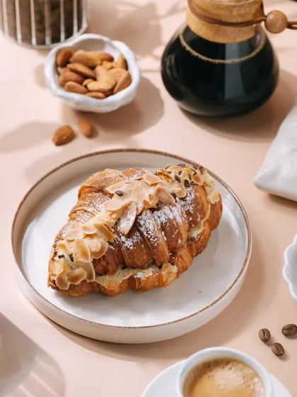 A bright and inviting shot of an almond croissant and coffee, perfect for a bakery's menu or social media. I styled this to create a perfect morning mood, highlighting the flaky pastry and fresh ingredients to attract customers.