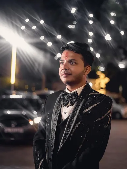 A groom portrait taken outdoors at night, with car headlights and string lights creating a dynamic and urban feel. This shot shows my ability to use any environment to create interesting and stylish photos.