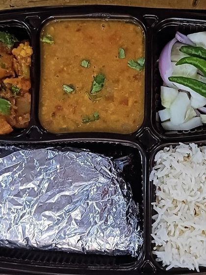 A classic comfort meal of dal, aloo gobhi, rice, and roti. The side of green chillies and salad adds a fresh and spicy kick.