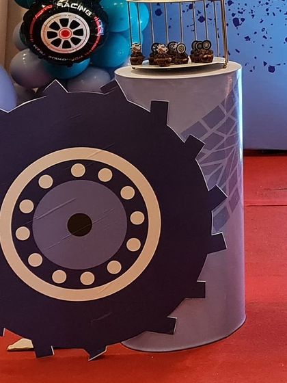 A large gear-shaped prop and themed pedestal for a race car party. These custom-made props add a unique and immersive element to the decoration.