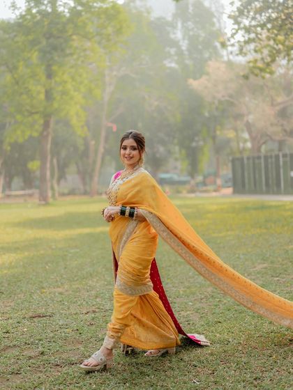 A beautiful shot of a bride in her yellow Nauvari saree, walking in the park. The flowing saree and elegant hairstyle create such a graceful picture.