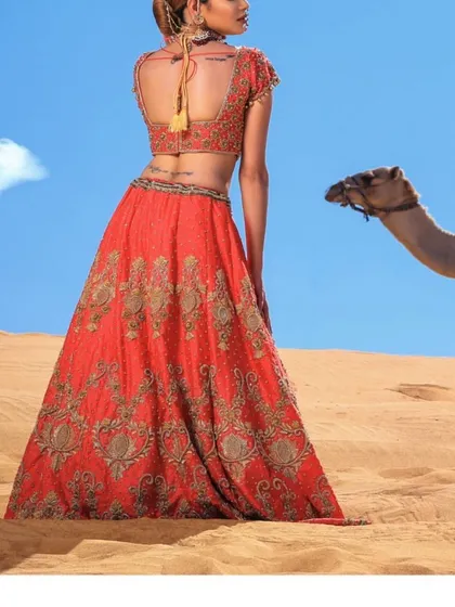 A whimsical and unique shot featuring the bride in her zardosi lehenga in a desert landscape, creating a stunning contrast of color and texture.