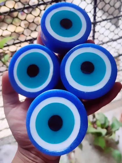 Holding a stack of four evil eye soaps to show their thickness and quality.