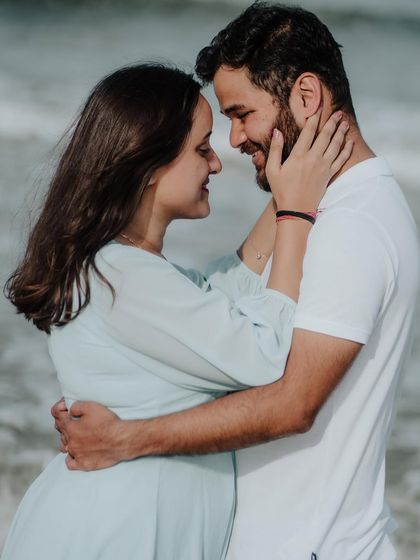 A tender close-up on the beach, focusing on the gentle touch and loving gaze between the couple.