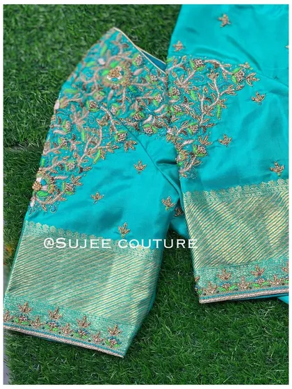 A full view of the teal blouse, showing the embroidered body and the contrasting brocade sleeves. This piece showcases a wonderful blend of color and texture.