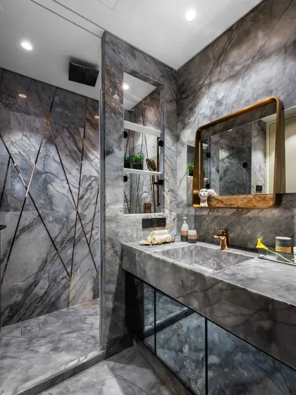 In this Mumbai residence, the bathroom is transformed into a private sanctuary of 'marbelous' splendour. We enveloped the space in dramatic grey marble, using its natural veining as a form of art. The custom brass-framed mirror and integrated sink demonstrate our focus on bespoke details and material excellence.