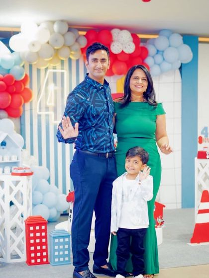 A happy family portrait at a Paw Patrol party. The backdrop features a vibrant balloon arch and character-themed props, creating a perfect photo opportunity.