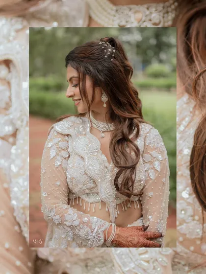 A detailed close-up of the bride, focusing on her soft smile and elegant hairstyle. The natural, leafy background complements her intricate white outfit perfectly.