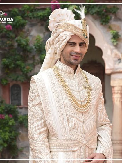A smiling groom, exuding confidence and joy. His Shauhar sherwani, with its pearl necklace and embellished safa, completes the picture of a happy, royal groom.