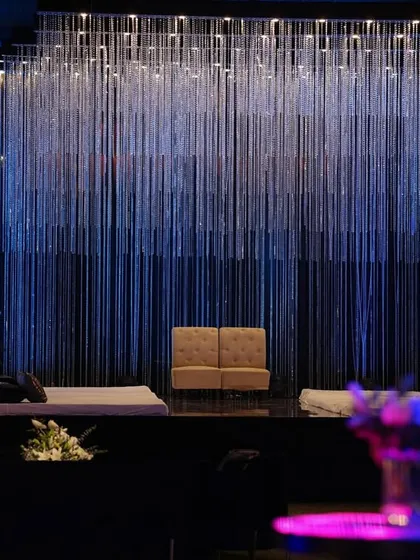A closer look at the crystal cascade stage, where the serene shimmer of the backdrop contrasts with the modern addition of disco balls and lush florals on either side.