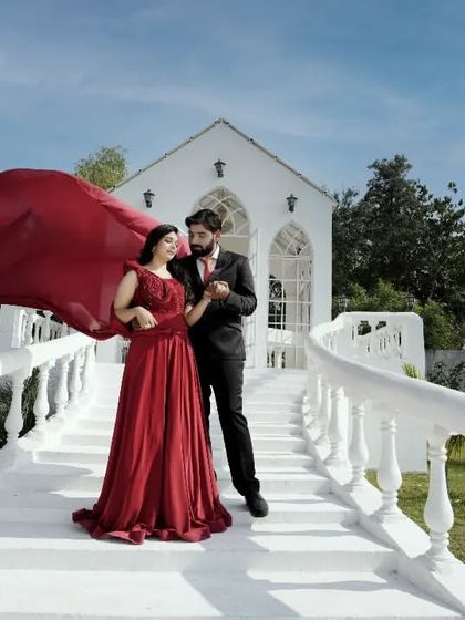 A grand, fairytale-like shot on a white staircase. The flowing red gown and the elegant setting create a very romantic and cinematic image.