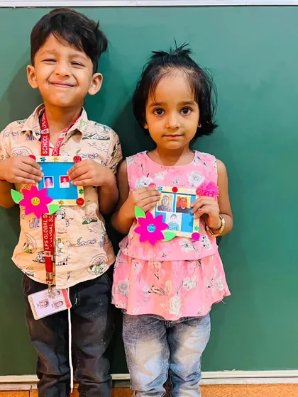 Two more proud students with their completed photo frames, decorated with colorful flowers.