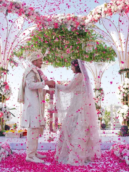 A shower of petals during the varmala ceremony, a moment of pure, uncontainable joy. Our goal is to freeze these energetic, happy moments in time, preserving the vibrant spirit of your celebration.