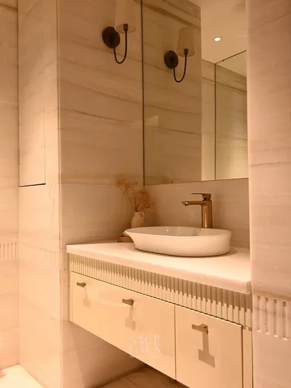 This powder room features a clean, minimalist aesthetic. The floating vanity with reeded detailing, vessel sink, and soft wall sconces create a serene and sophisticated atmosphere. The all-neutral palette feels both modern and timeless.