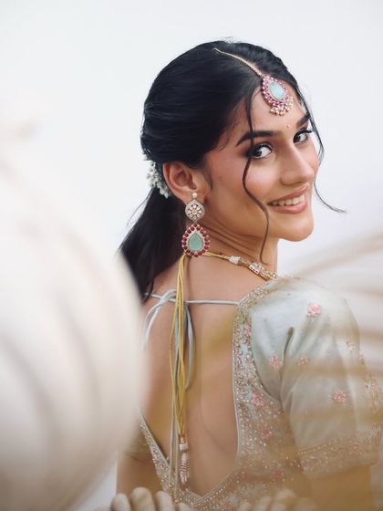 I love this over-the-shoulder shot. It highlights the beautiful smile, the glowing skin, and the intricate details of the jewelry and hair.