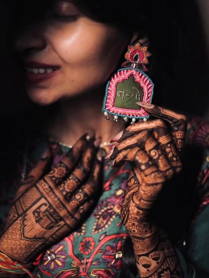 An artistic shot of a bride with her mehandi, highlighting her unique earring. We love capturing these beautiful details.