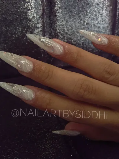 This demonstrates my skill in creating dramatic length and shape with these sharp stiletto extensions. The design features an inbuilt milky white and glitter effect for a look that is both elegant and fierce.