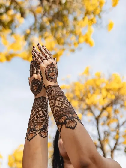 An artistic shot of a client's mehndi against a backdrop of beautiful yellow flowers, capturing the essence of a spring celebration.