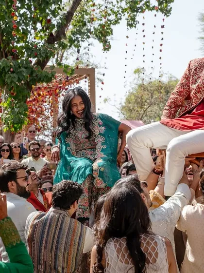 Smiti and Nilesh are hoisted up on shoulders during a fun-filled celebration. The energy of the crowd and the couple's laughter make this a perfect snapshot of wedding masti.