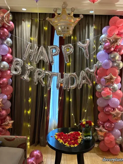 This birthday setup combines balloons and flowers for a romantic touch. The heart made of red roses on the table adds a beautiful focal point to the festive balloon decor.