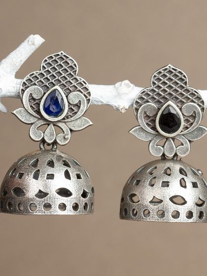 We do everything with heart. These oxidized silver jhumkas with a cut-out dome design are available in blue and black stone options.