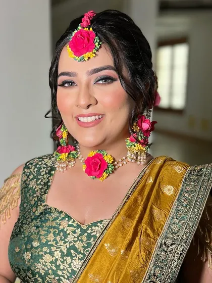 A beautiful Mehendi look with a focus on glowing skin and defined eyes. The floral jewelry adds a traditional and festive touch.