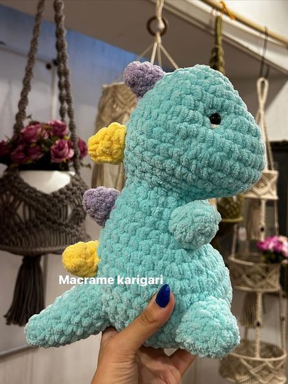 Our handmade crochet dinosaur in its natural habitat, surrounded by our macrame plant hangers. It's a perfect blend of our two favorite crafts.