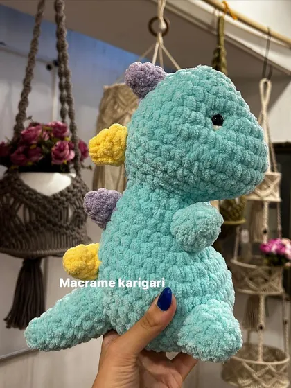 Our handmade crochet dinosaur in its natural habitat, surrounded by our macrame plant hangers. It's a perfect blend of our two favorite crafts.