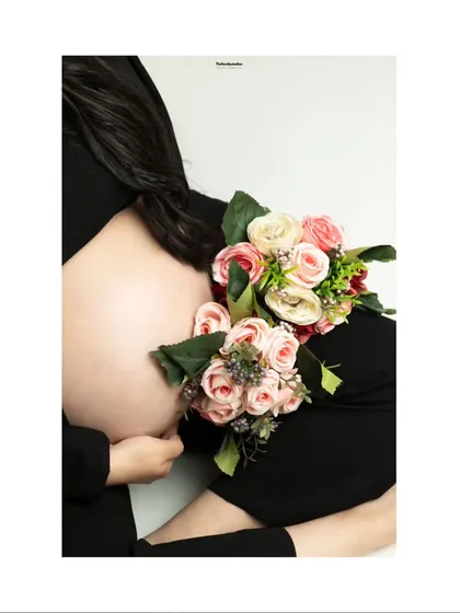 An artistic close-up focusing on the baby bump, adorned with a beautiful bouquet of pink and white roses. This minimalist shot celebrates the beauty of pregnancy in a simple and elegant way.