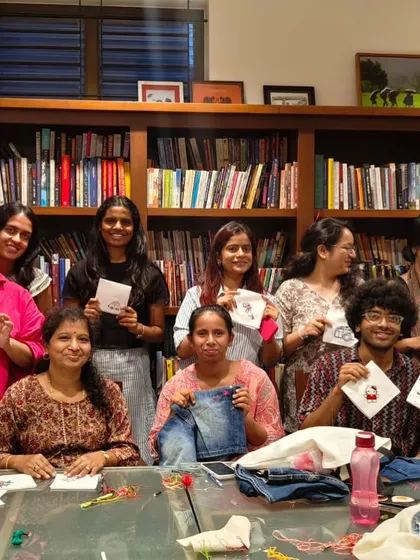 A group of happy participants holding up their finished embroidery work from a creative workshop.
