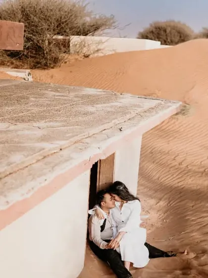 An intimate moment shared in a sand-swept structure in the Abu Dhabi desert. This cozy, sheltered shot contrasts with the vastness of the surrounding dunes.