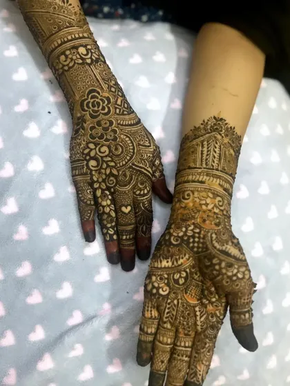 A lovely bridal design that combines floral elements with traditional architecture-inspired patterns on the forearm.