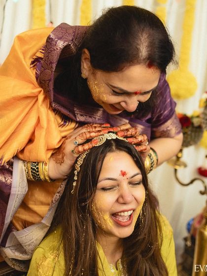 A moment of pure joy and laughter as the bride is covered in turmeric paste by her loved ones during the Haldi ceremony.