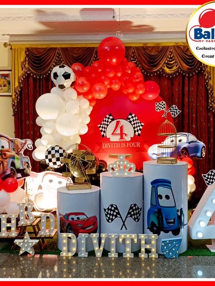A high-octane Cars-themed fourth birthday party. The setup features Lightning McQueen and Mater cutouts, a racetrack-themed backdrop, and a large light-up number '4'.