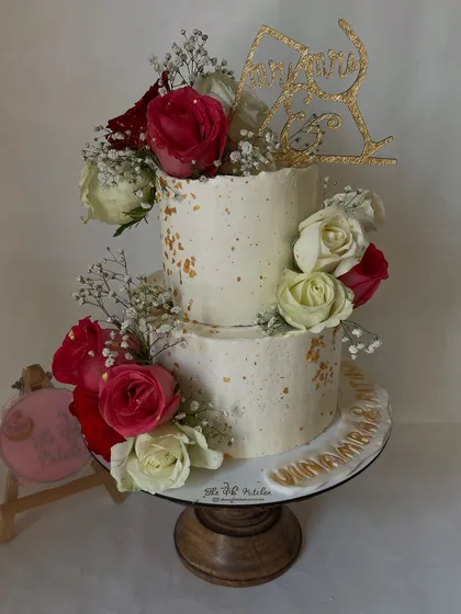 I designed this rustic two-tier cake specifically for a Roka ceremony, complete with a custom topper. The textured buttercream, gold dust speckles, and arrangement of fresh red and white roses create a chic and celebratory look.