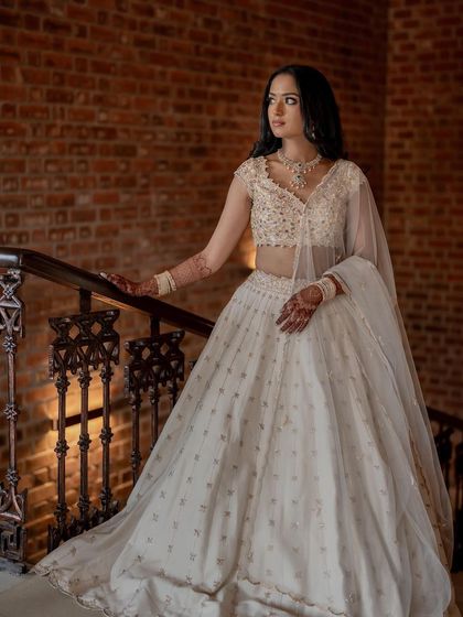 A full-length portrait of this bride in her elegant white lehenga, looking ethereal and beautiful.