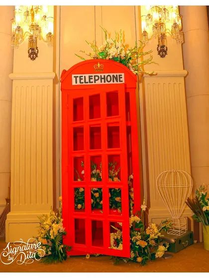 A life-sized red telephone booth prop, filled with flowers, served as a unique and beautiful photo opportunity for guests at the London-themed party.