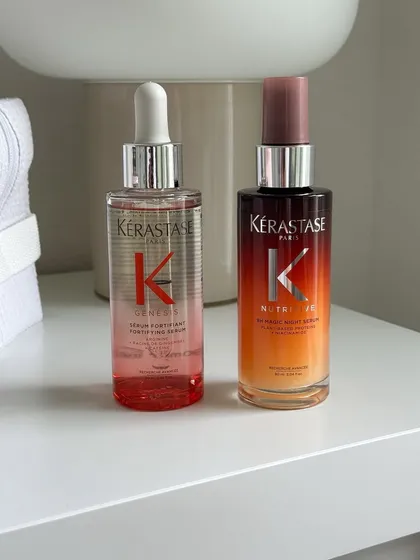 A clean, aesthetic shot of Kérastase Genesis and Nutritive serums on a modern nightstand. We offer these luxury products for you to continue your hair care routine at home.