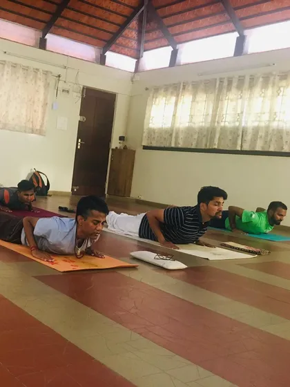 Students holding Bhujangasana, or cobra pose, during a Yogasanas session. This posture is excellent for strengthening the spine, but precision is key. I guide everyone to engage their muscles correctly to build strength safely and effectively.