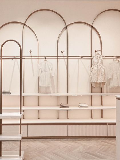A straight-on view of the custom wall shelving and clothing racks. The design provides ample space for both folded and hanging garments, ensuring the display feels organized and uncluttered.