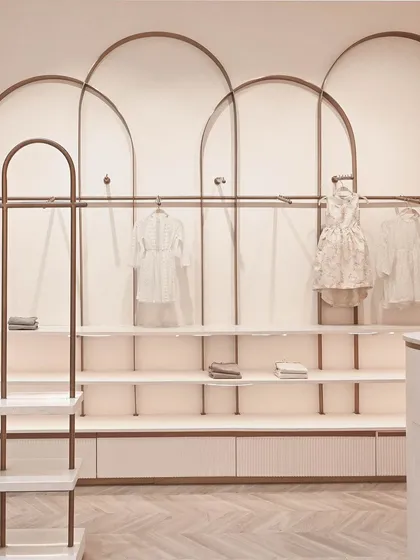 A detail of the wall-mounted display units, where overlapping rose gold arches create a beautiful and rhythmic pattern for hanging and shelving clothes.