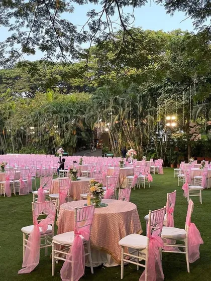 The guest seating area was a sea of pink, with beautifully decorated tables and chairs spread across the lush green lawn, creating a vibrant and festive atmosphere.