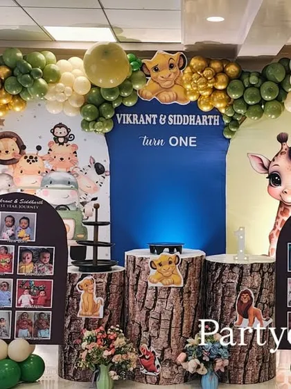 Another take on our popular jungle theme, this one for a first birthday. It features personalized photo boards, tree-trunk-style plinths, and a full balloon arch with green and gold accents.