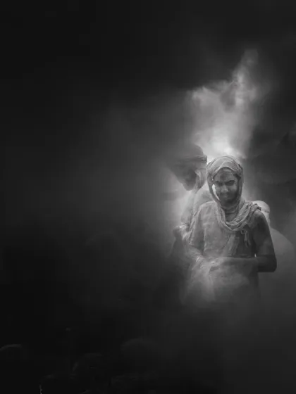 A black and white photograph from Braj ki Holi. The soft, ethereal light filtering through the colored powder creates a ghostly and beautiful effect.