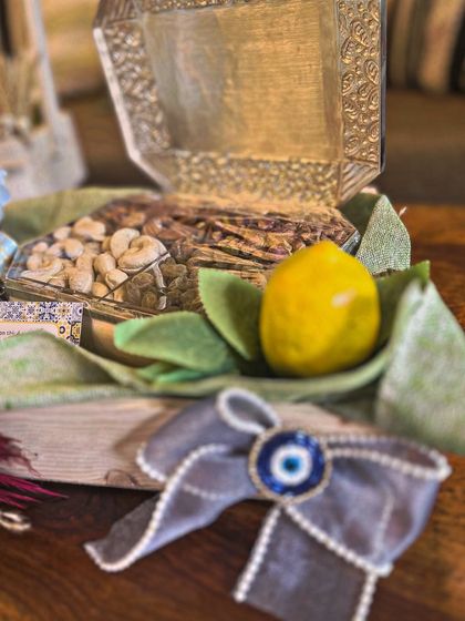 A silver dry fruit box is presented with a traditional lemon and an evil eye charm, key elements of the Moroccan theme. The bow is also adorned with a beaded evil eye, tying every detail together.